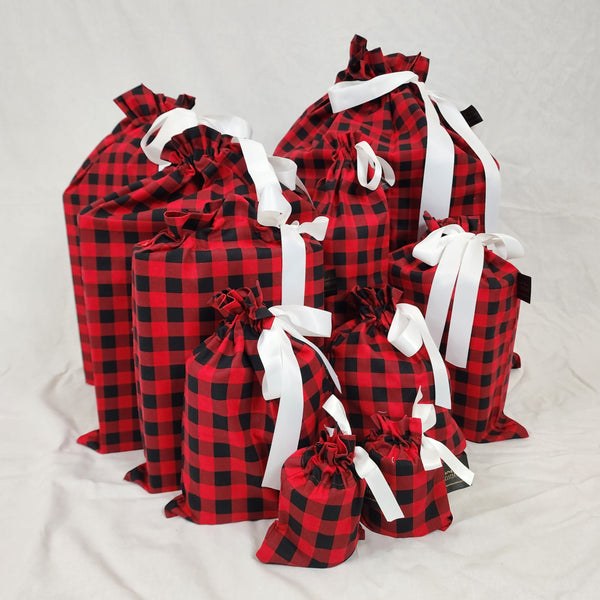 A photo showing a set of Sew Your Own Gift Bags in American Plaid all sewn up. The fabric is red and black checked and the bags are tied with white satin ribbon.