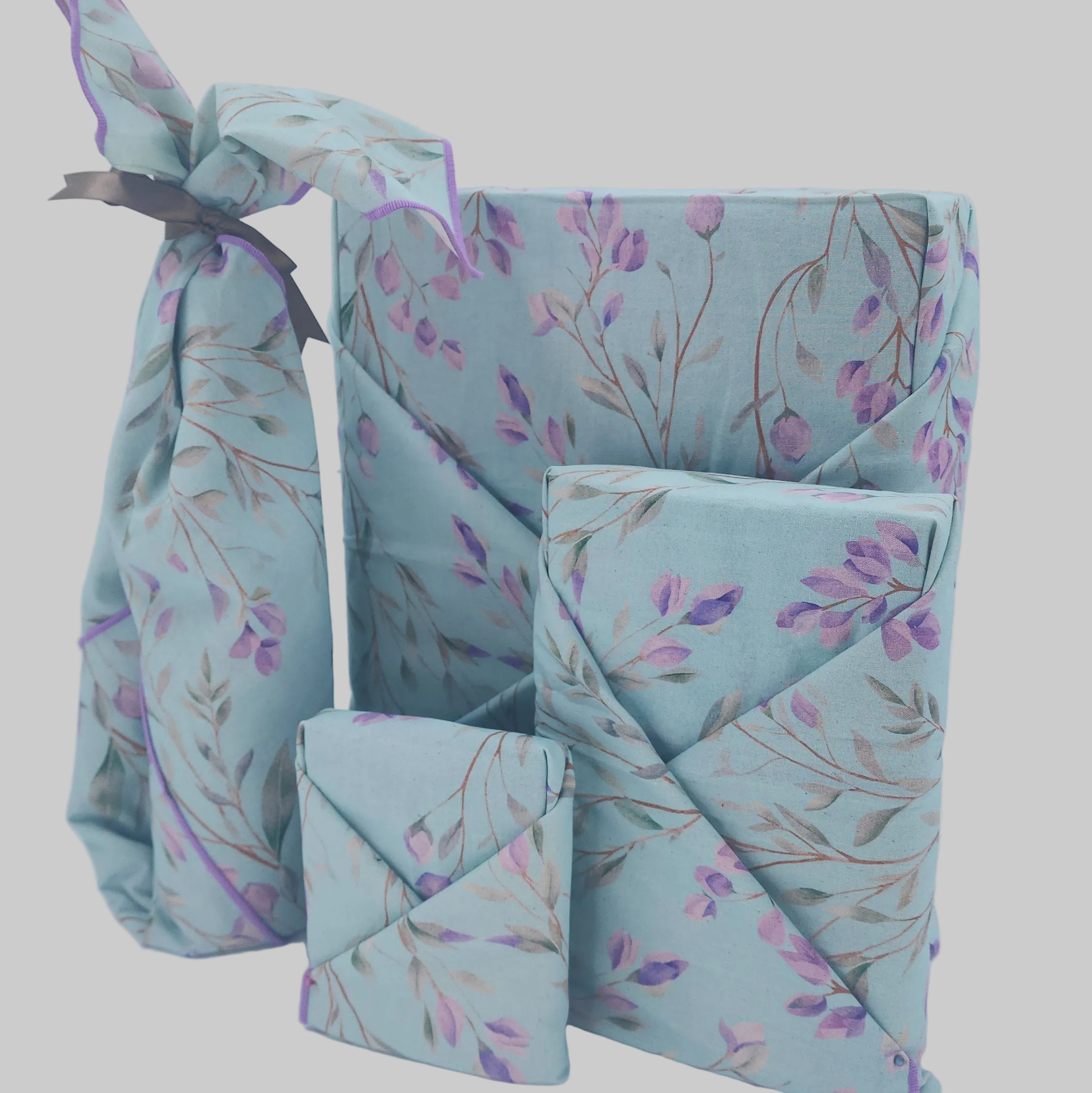 Pack of 4 matching furoshiki wraps in a pale blue and lavender patter, with lavender edging.