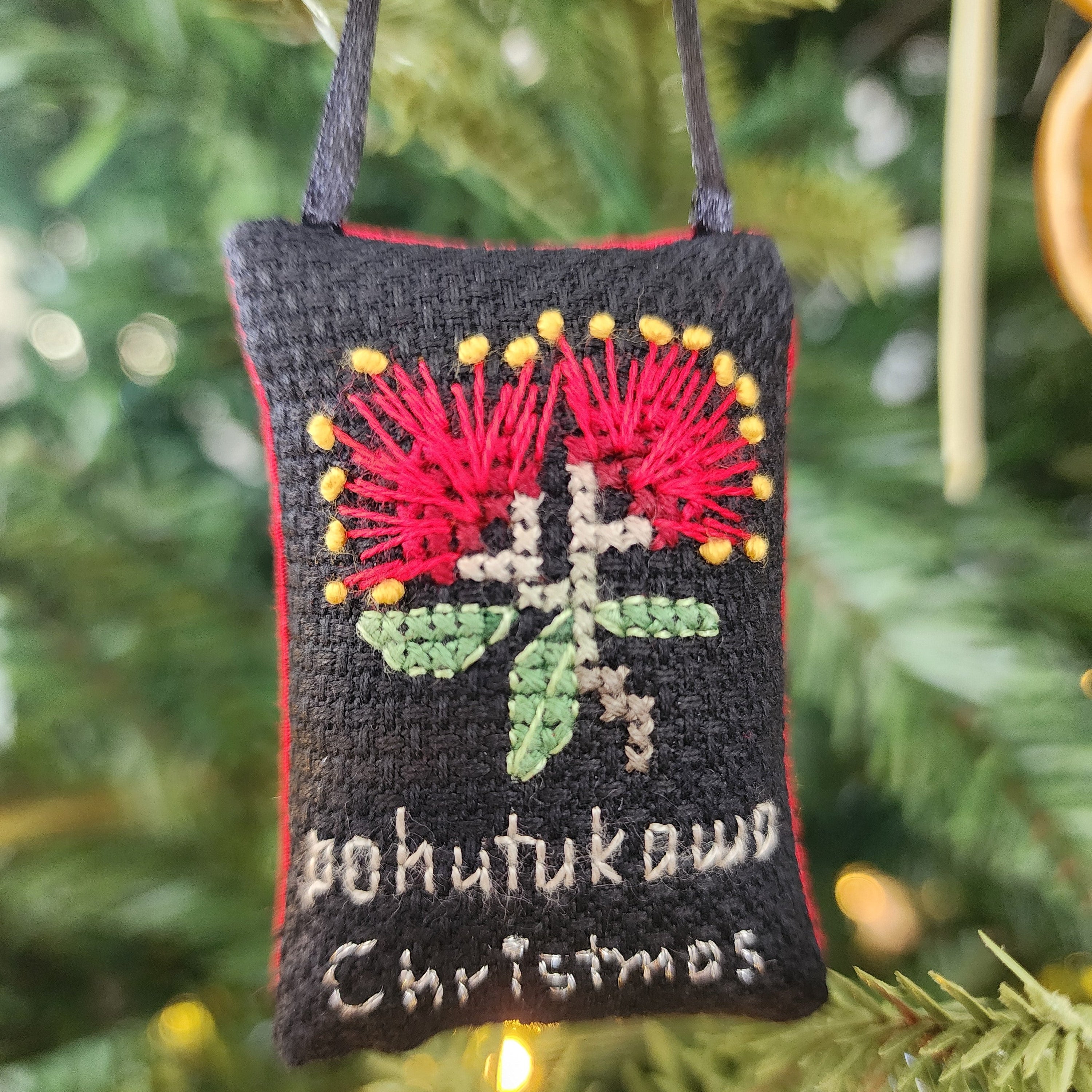 Cross stitch Christmas ornament with Pohutukawa Christmas on a black background