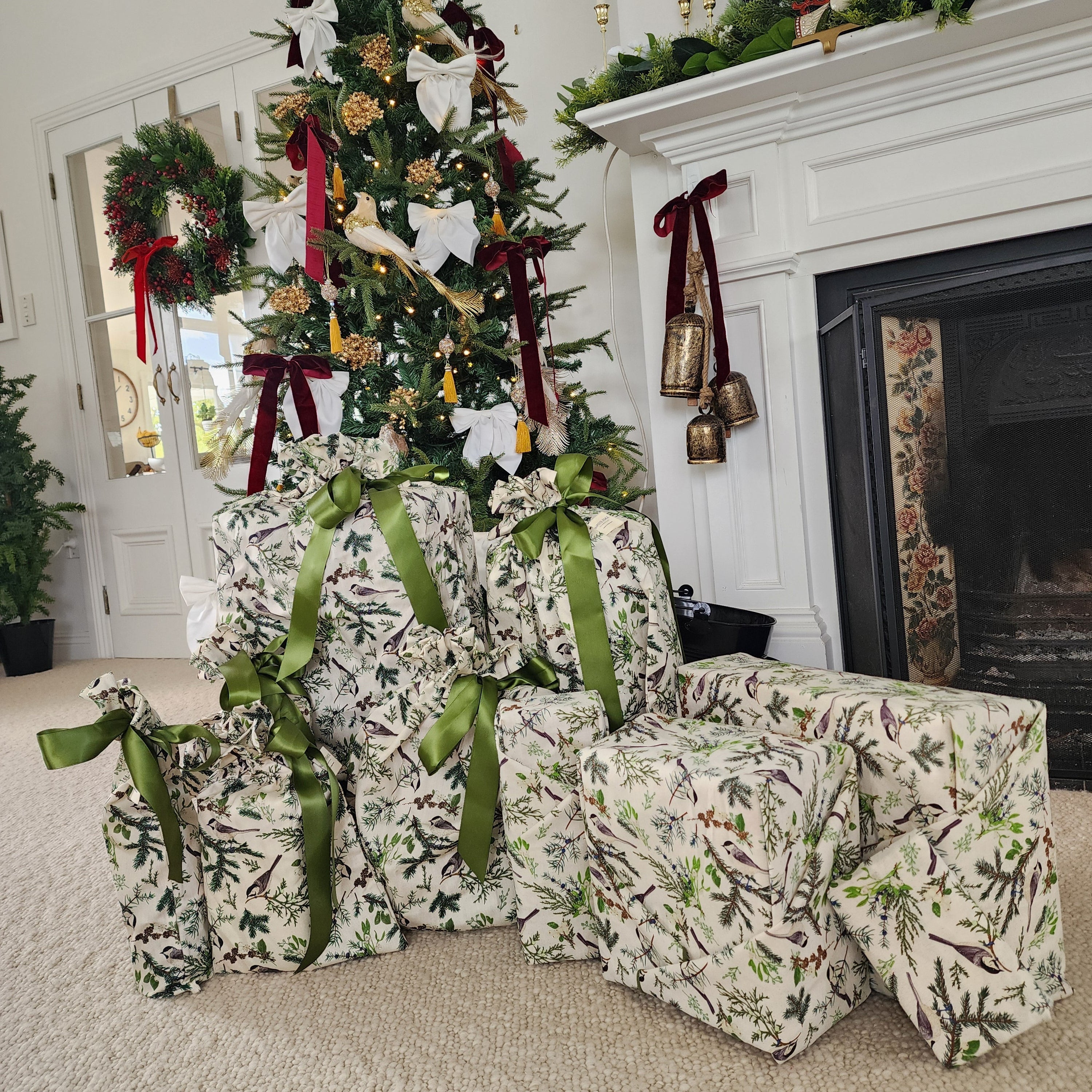 A collection of Christmas wrapped gifts in a matching green and white holly patterned cotton, arranged around a decorated Christmas tree in a living room setting.