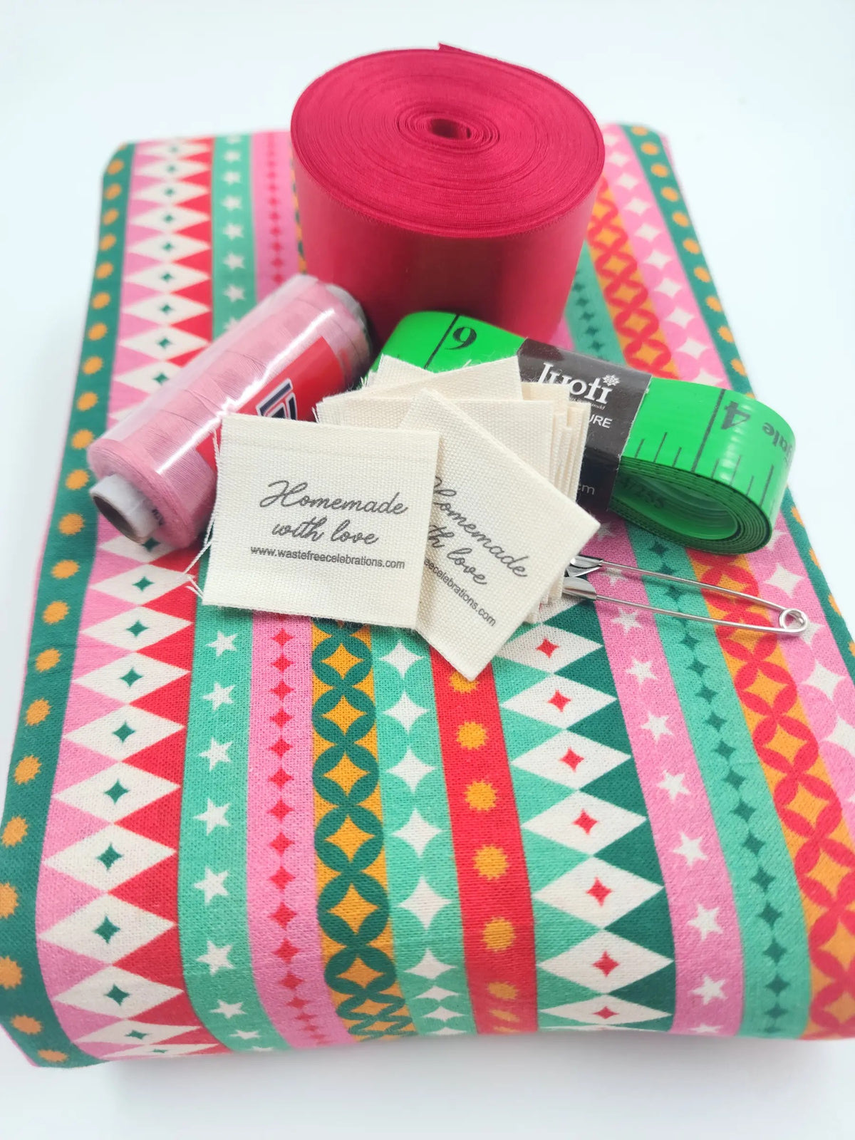 Fiesta Sew Your Own reusable gift bag kit — pre-cut fabric in bright geometric stripes with red ribbon, thread, tape measure, safety pin and 'Homemade with love' labels