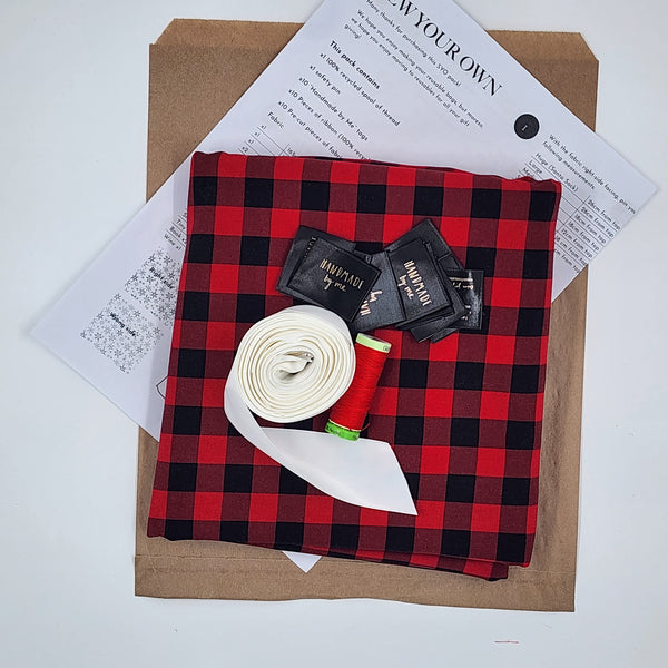 A photo showing the contents of a Sew Your Own Gift Bag set in American Plaid. There is fabric, ribbon, thread, tags and instructions.