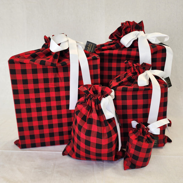 Set of five reusable Christmas gift bags in American Plaid. Bags are black and red check with a white satin ribbon.