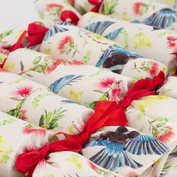 Close up of Flora and Fauna Re-Crackers (reusable eco-friendly Christmas Crackers or Bon bons). This fabric features tui, kowhai and pohutakawa on a white background. Finished with red satin ribbons.