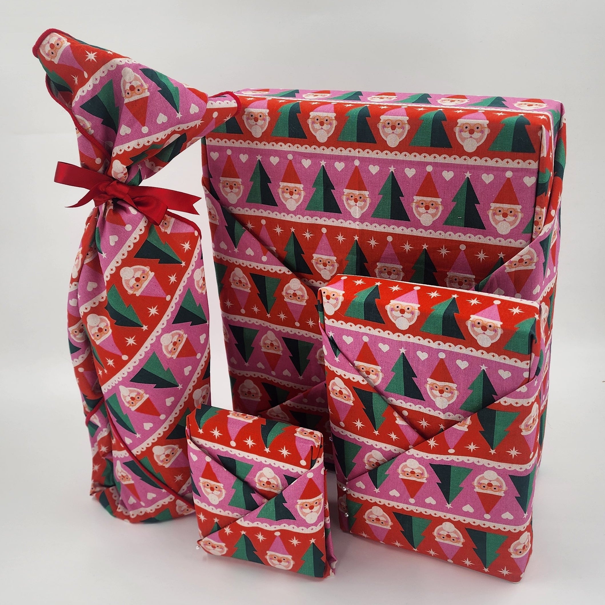 Furoshiki cotton gift wrap on on four gifts in red, pink, green and white santa design