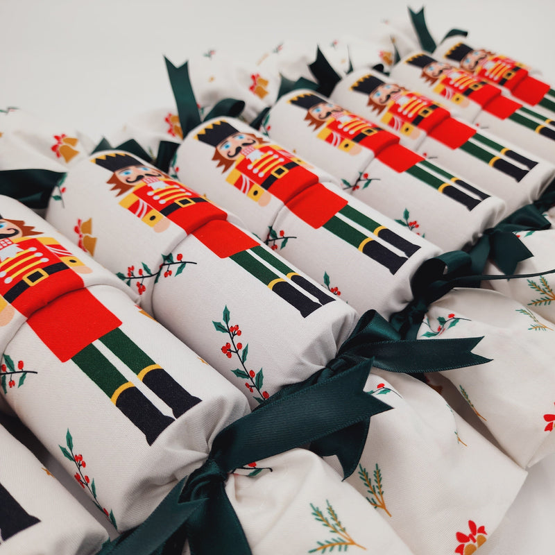 Eight Re-Crackers (reusable Christmas Crackers or bon bons) in nutcracker design. Featuring a large nutcracker figure on a white background with dark green ribbon