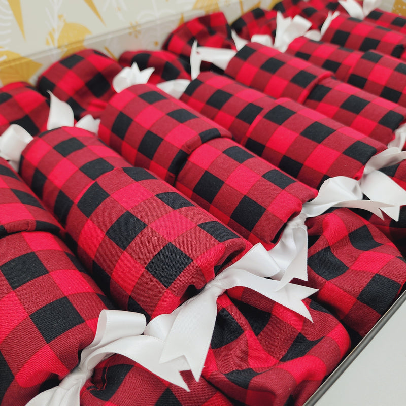 Close up photo of American Plaid Sew Your Own Re-Crackers (reusable Christmas crackers or bon bons) once they have been made up. The fabric is red and black check, and they are fastened with dark green ribbon.