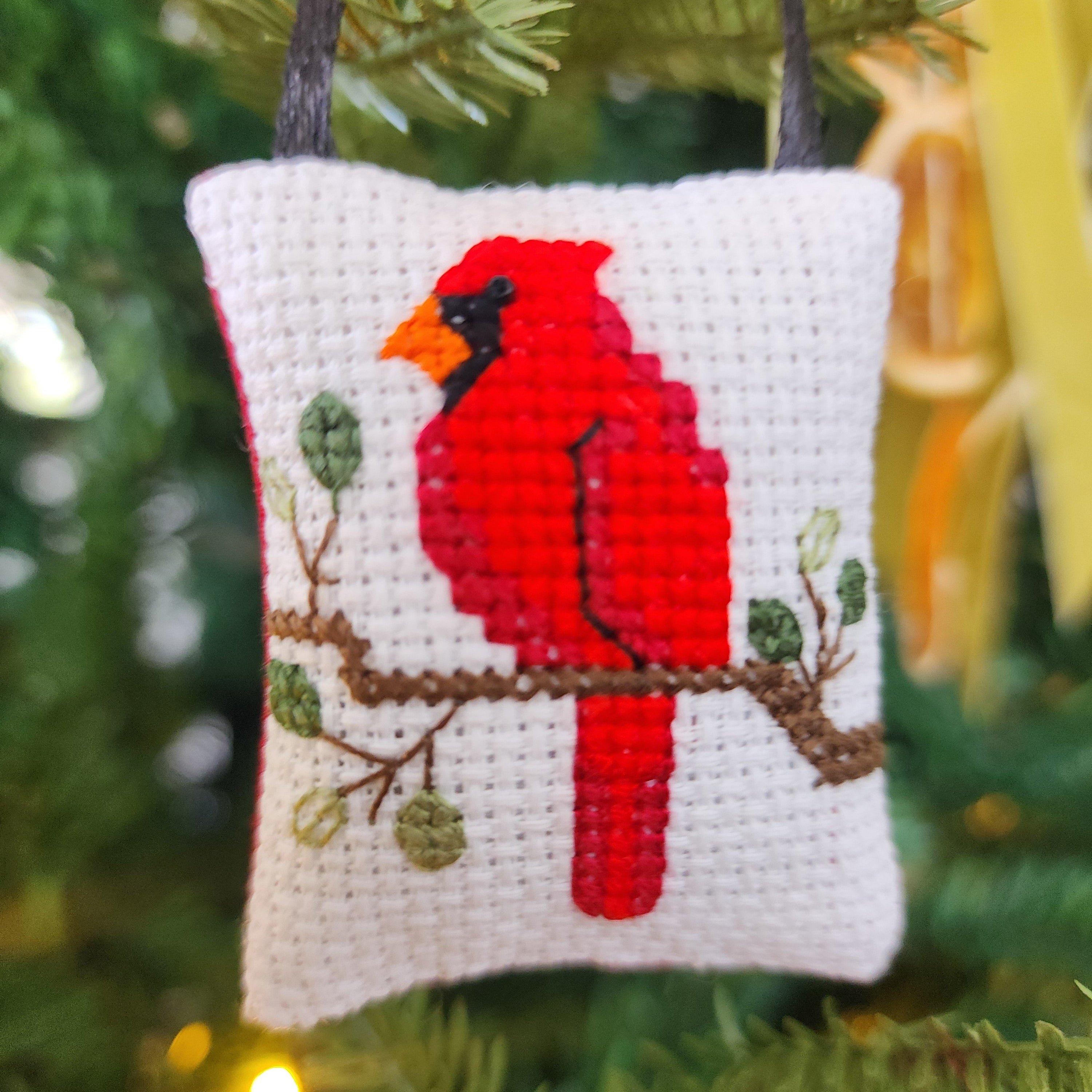 Cross-stitched cardinal ornament on a Christmas tree