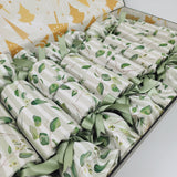 Close up photo of Australiana Watercolour Sew Your Own Re-Crackers (reusable Christmas crackers or bon bons) once they have been made up. The fabric has taupe and white stripes with green leaves, and they are fastened with green ribbon.