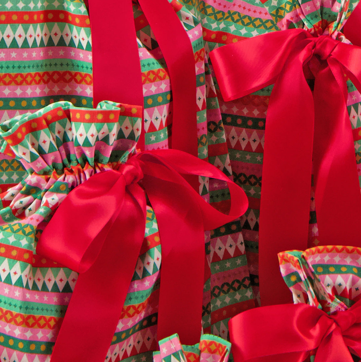 Fiesta fabric close-up — bold geometric stripe print in red, pink, green and gold