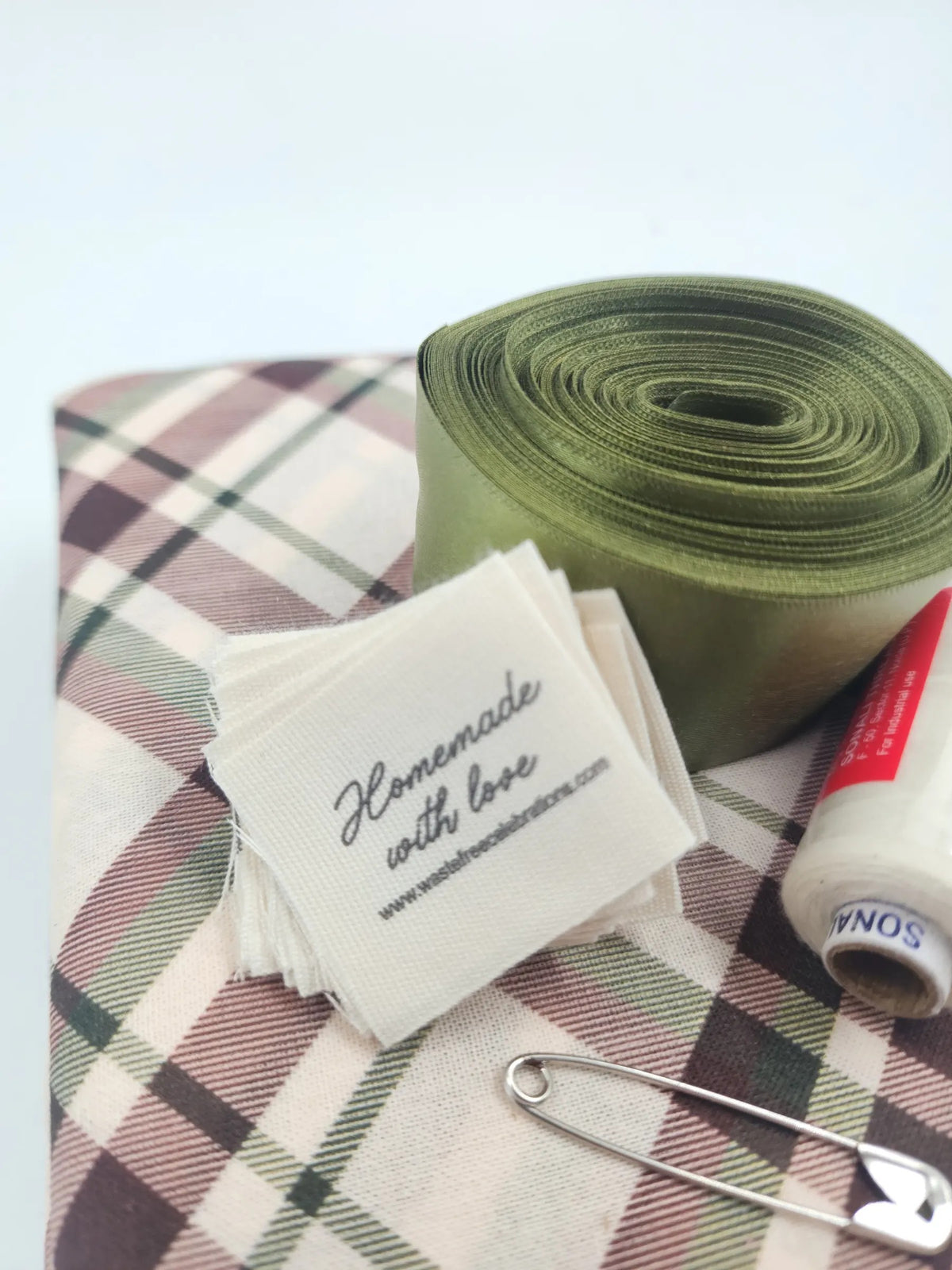 Close-up of the Tartan Sew Your Own kit — 'Homemade with love' sew-in labels, olive ribbon and tartan fabric