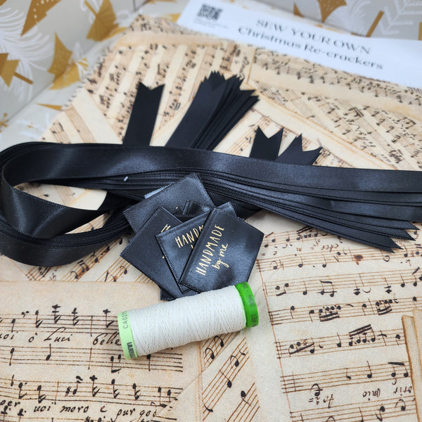Closeup photo of Beethoven and Bronte fabric, with tags, black satin ribbon and thread.