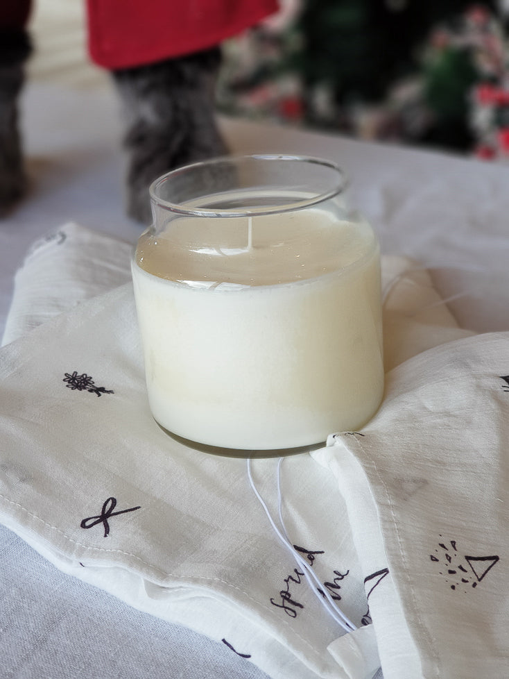 A candle in a glass jar sitting on top of reusable tissue wrap