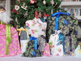 Photo shows a set of ten Mixed Kiwiana reusable gift bags filled and under the tree.
