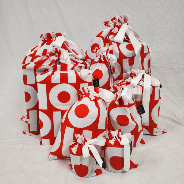 Set of ten reusable Christmas gift bags in HOHOHO. Bags are red with the words HOHOHO in large white lettering. Bags are tied with a white satin ribbon.