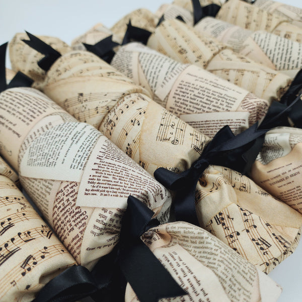Close up Beethoven and Bronte Re-Crackers (reusable Christmas Crackers or Bon bons). Crackers feature alternate images of Brontes writing and vintage sheets of music. Finished with Black Satin Ribbon.