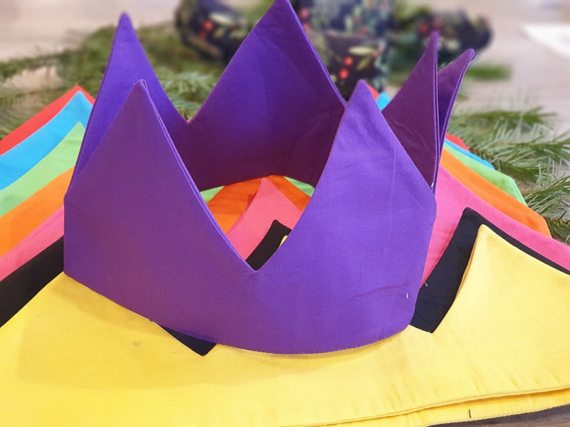 A purple reusable cotton crown sitting on top of a pile of other colourful reusable crowns