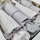 Boxed set of four Silver and Ice Re-Crackers (reusable Christmas Crackers or Bon-Bons). Fabric has a sliver motif with alternating white and grey background with silver ribbon.