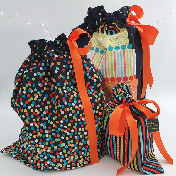 Set of four Time to Party reusable gift bags. The large bag features a birthday cake and the words “Time to Party”, the medium and Tiny are black with bright cascading polka dots and the small is in colourful stripes.