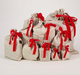 Photo shows a set of ten Luxury Linen and Velvet Reusable Gift Bags. Bags are made from natural coloured flax linen, secured with a red velvet ribbon.