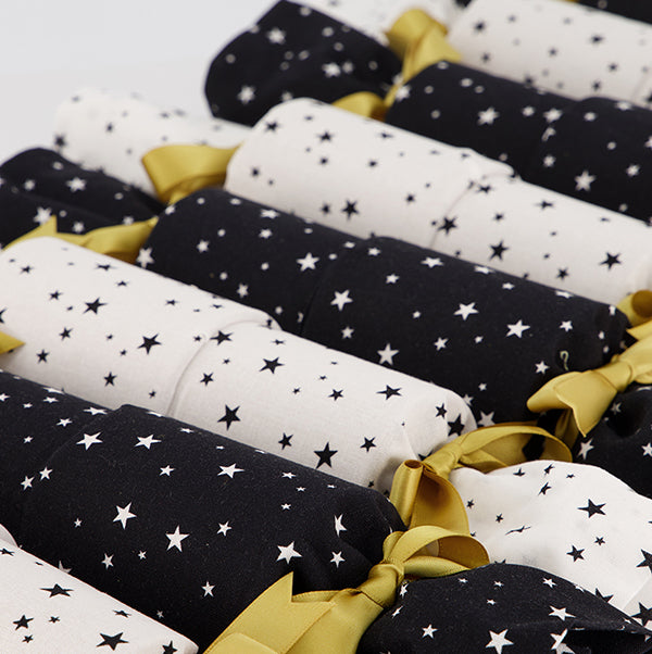 Close up of Starry Night Re-Crackers (reusable Christmas Crackers or Bon bons). Crackers alternate between white and black with contrasting tiny stars and gold satin ribbon.