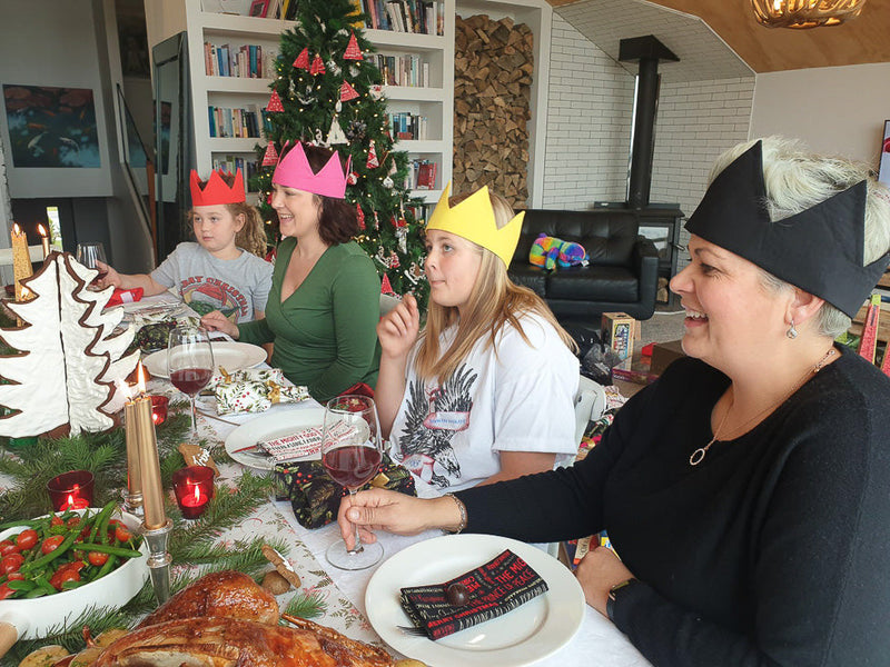 People sitting at a Christmas Dinner table wearing colourful reusable cotton crowns